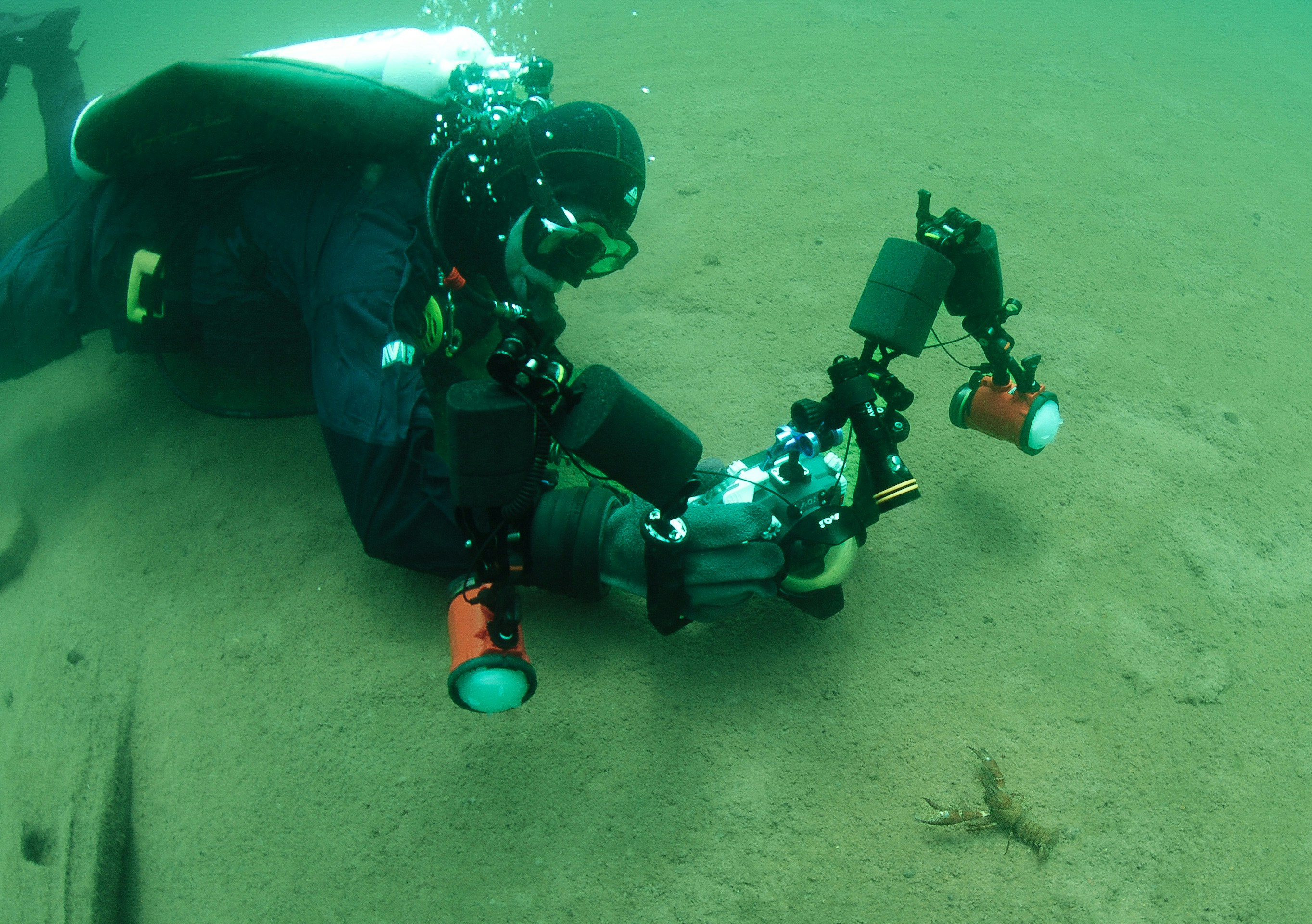 A scuba diver films underwater with specialized equipment