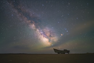 Milky way shines above an old, weathered boat.