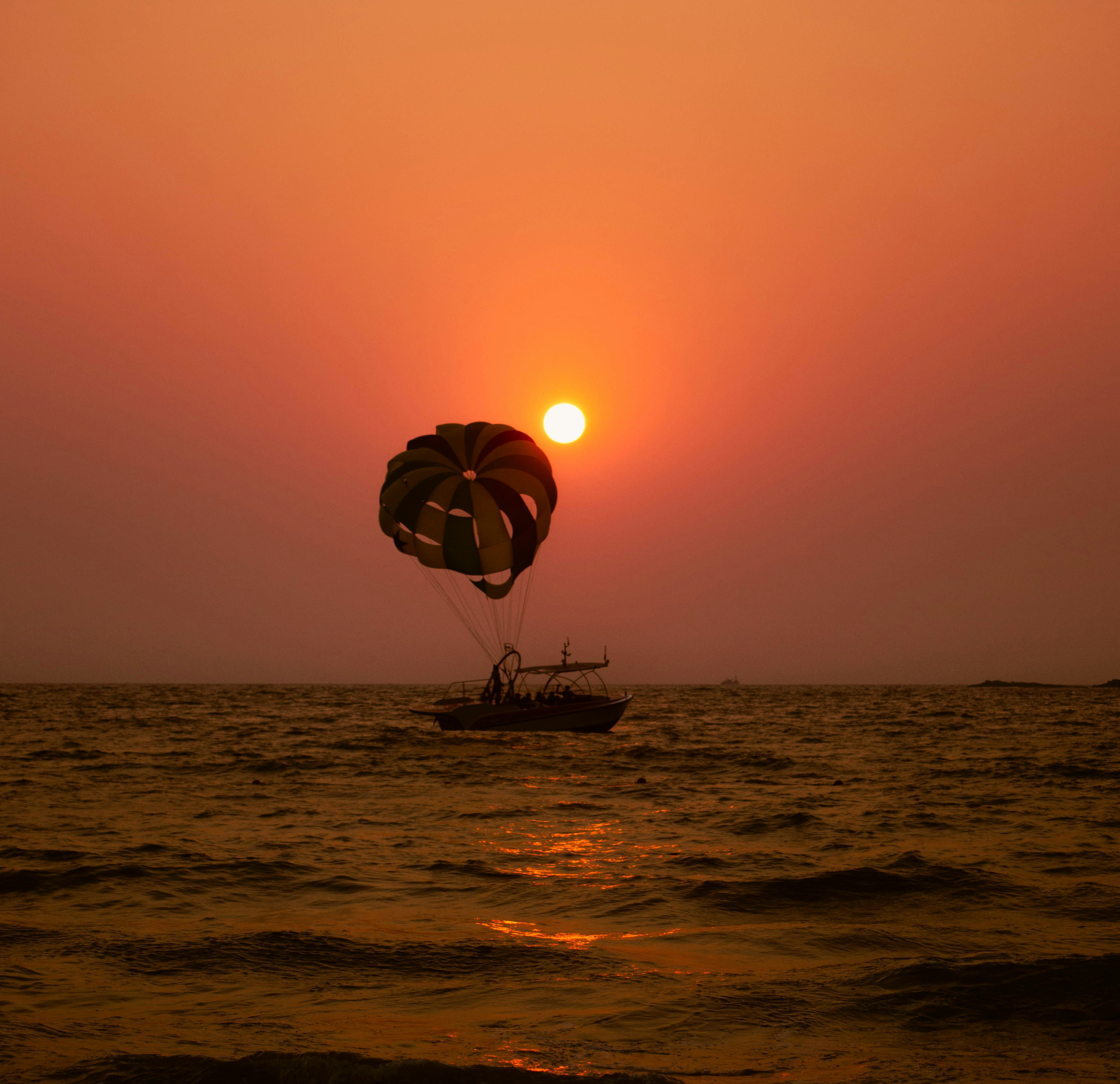 Parasailing over the ocean at sunset.