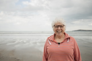 Happy woman smiles at the beach with an ocean background.