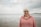Happy woman smiles at the beach with an ocean background.