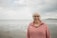 Happy woman smiles at the beach with an ocean background.