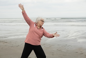 Woman exercises at the beach with outstretched arms.