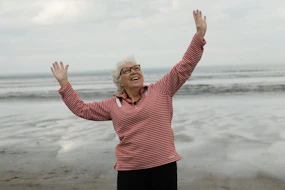 Woman raises arms on the beach with joy