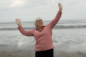 Woman raises arms on the beach with joy.