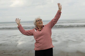 Woman raises arms on the beach with joy