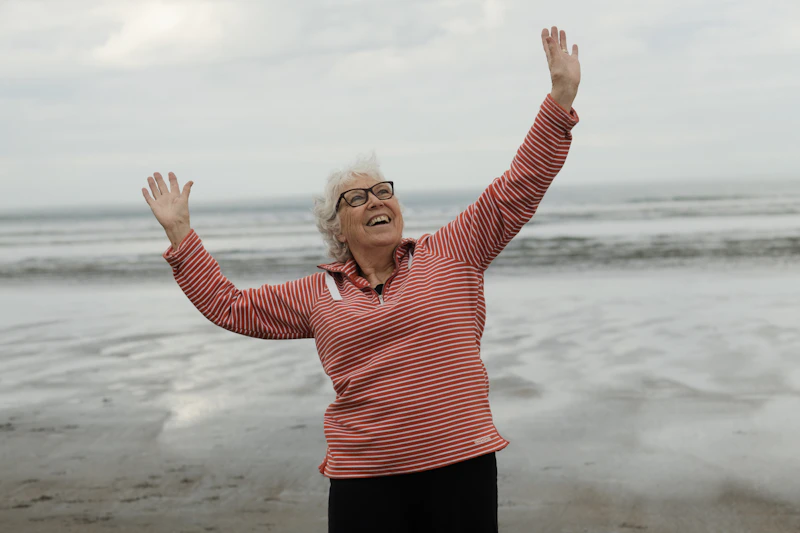 Woman raises arms on the beach with joy.