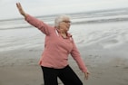 Woman practices tai chi on the beach.