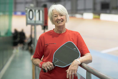 Woman smiles and holds a pickleball paddle.
