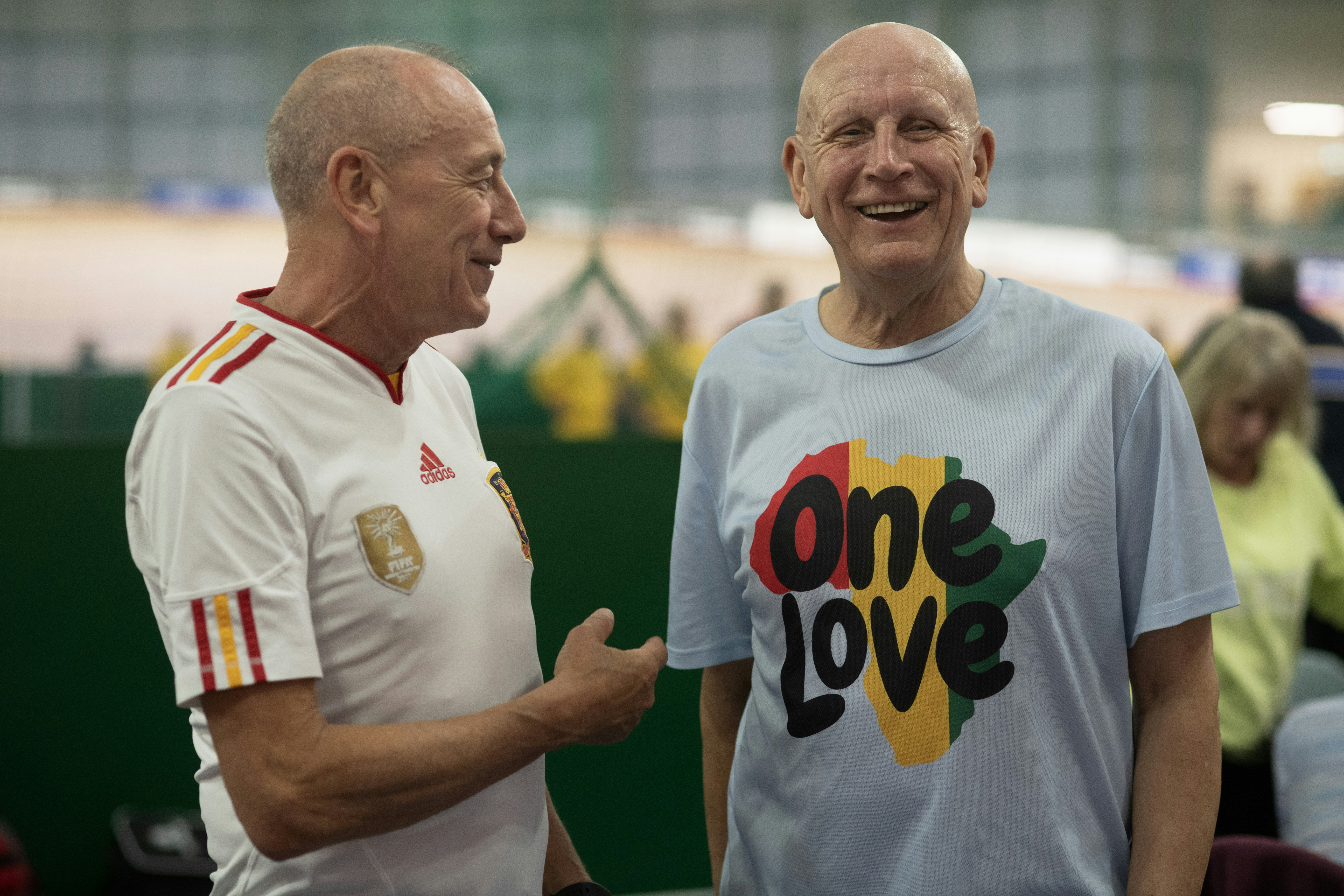 Two smiling men are talking to each other.