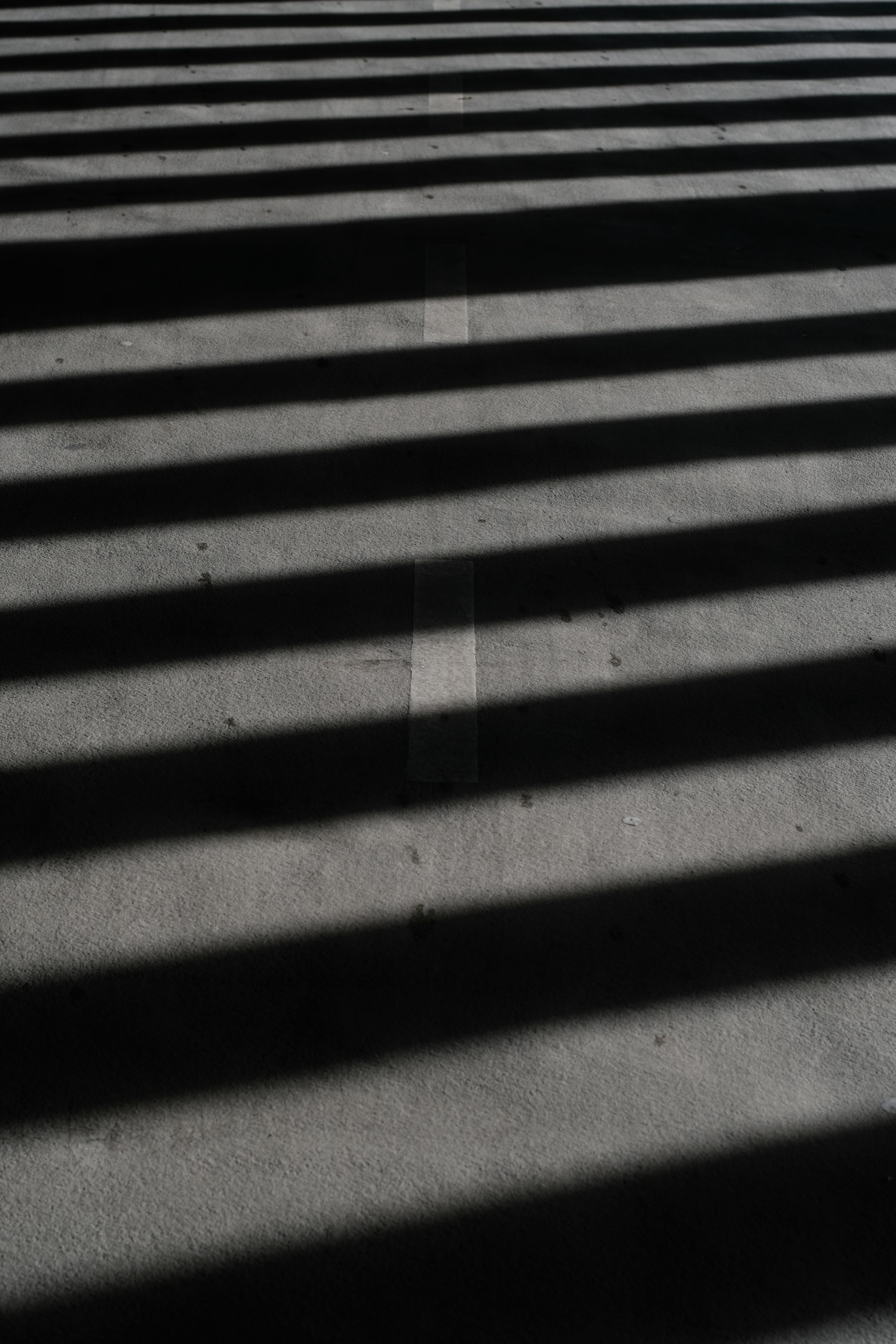 Shadows cast stripes across a concrete surface.