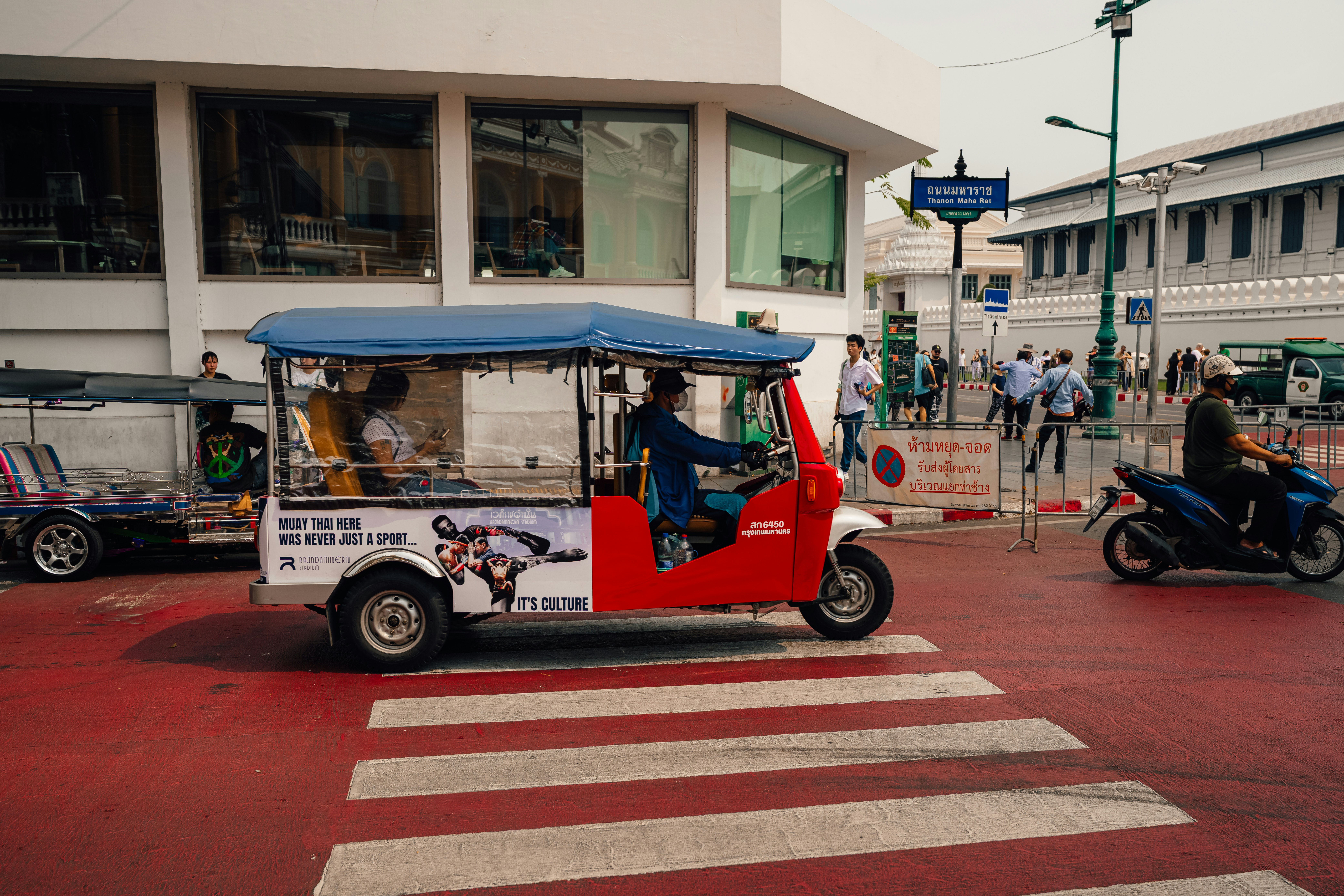 A tuk-tuk travels on a road in thailand. - Bangkok