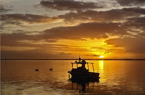 A boat silhouetted against a fiery sunset.