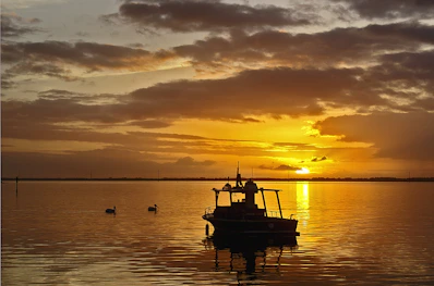 A boat silhouetted against a fiery sunset.