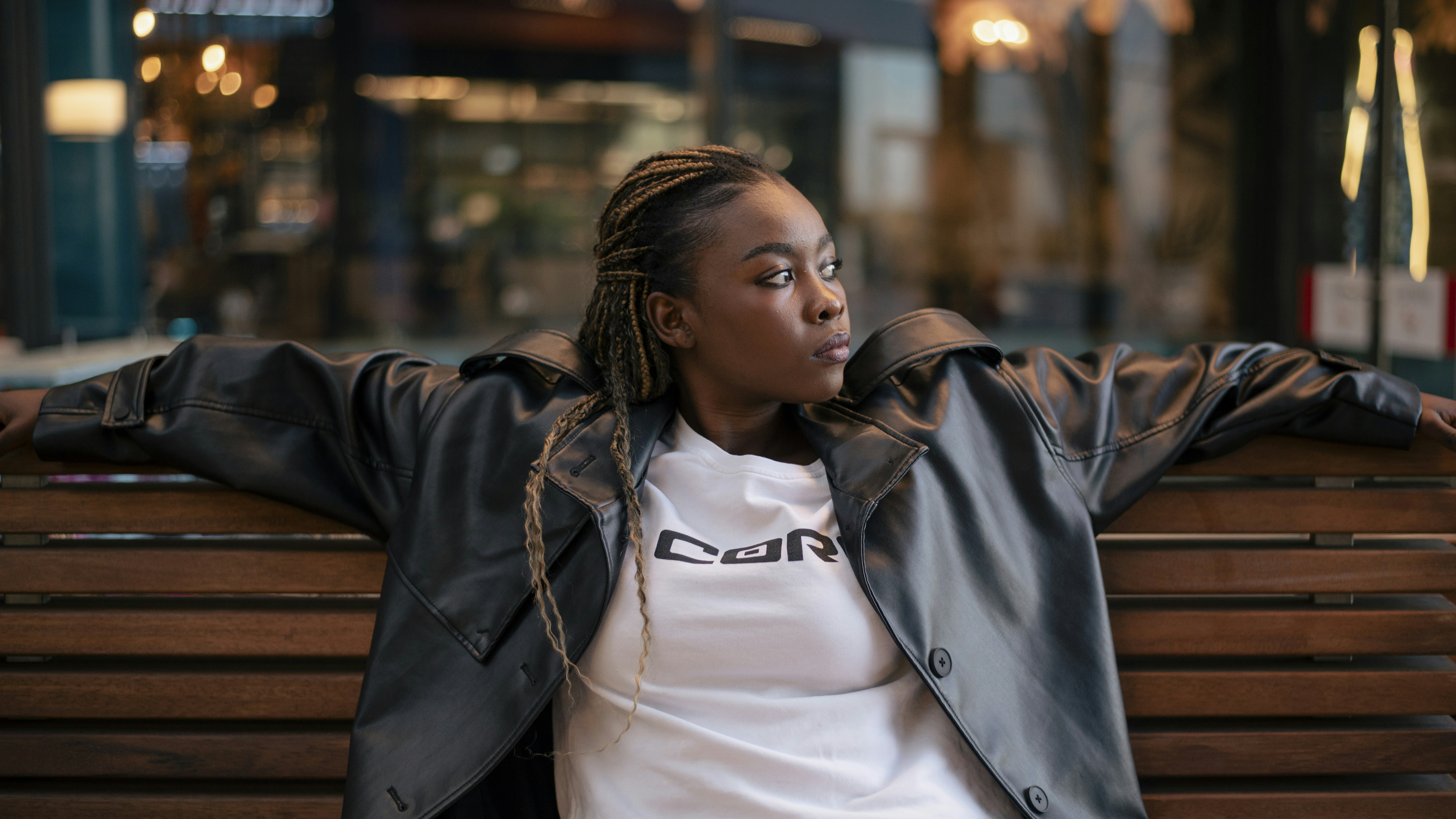 A woman relaxes on a bench, looking away.