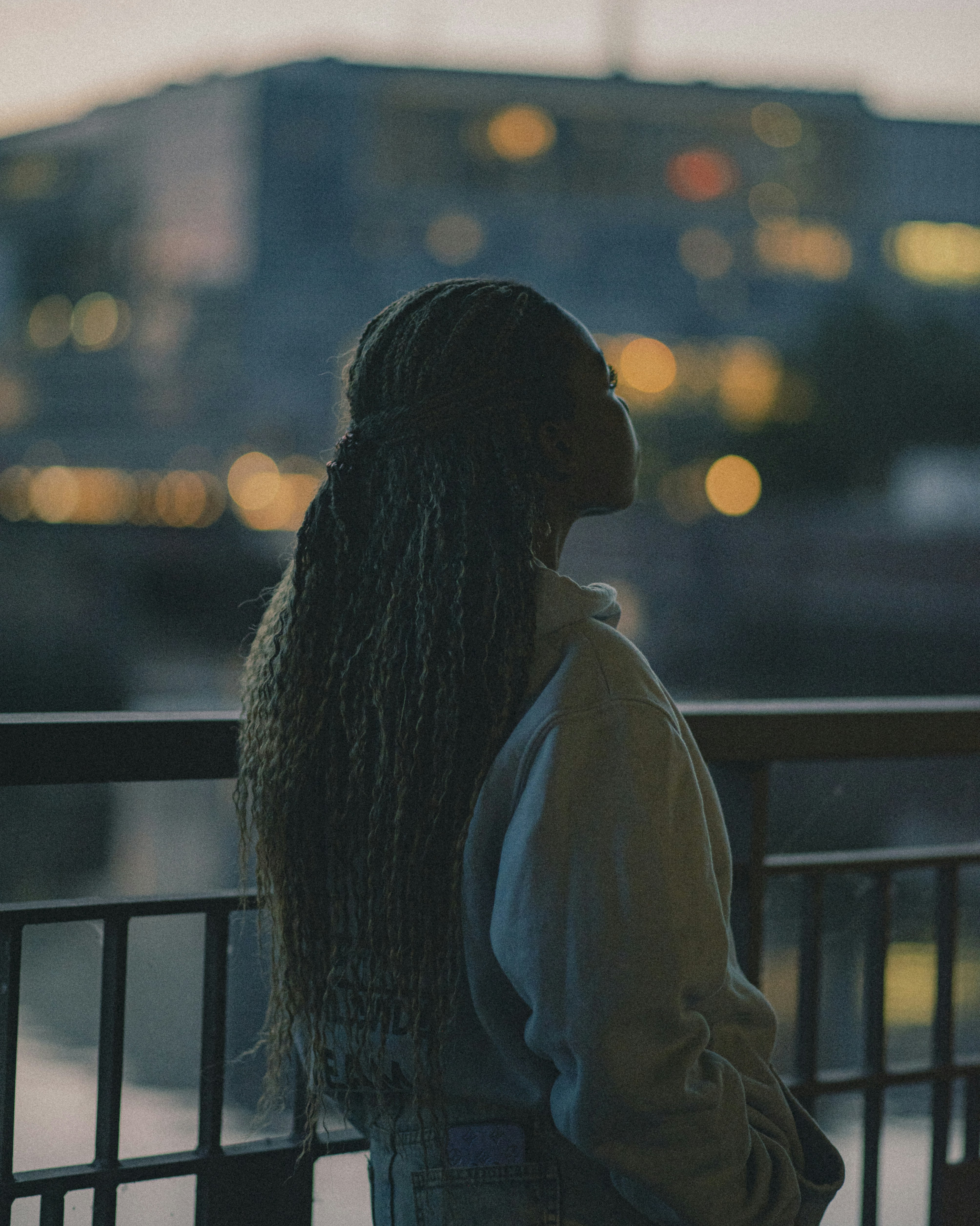 Woman looks toward a blurry city skyline.