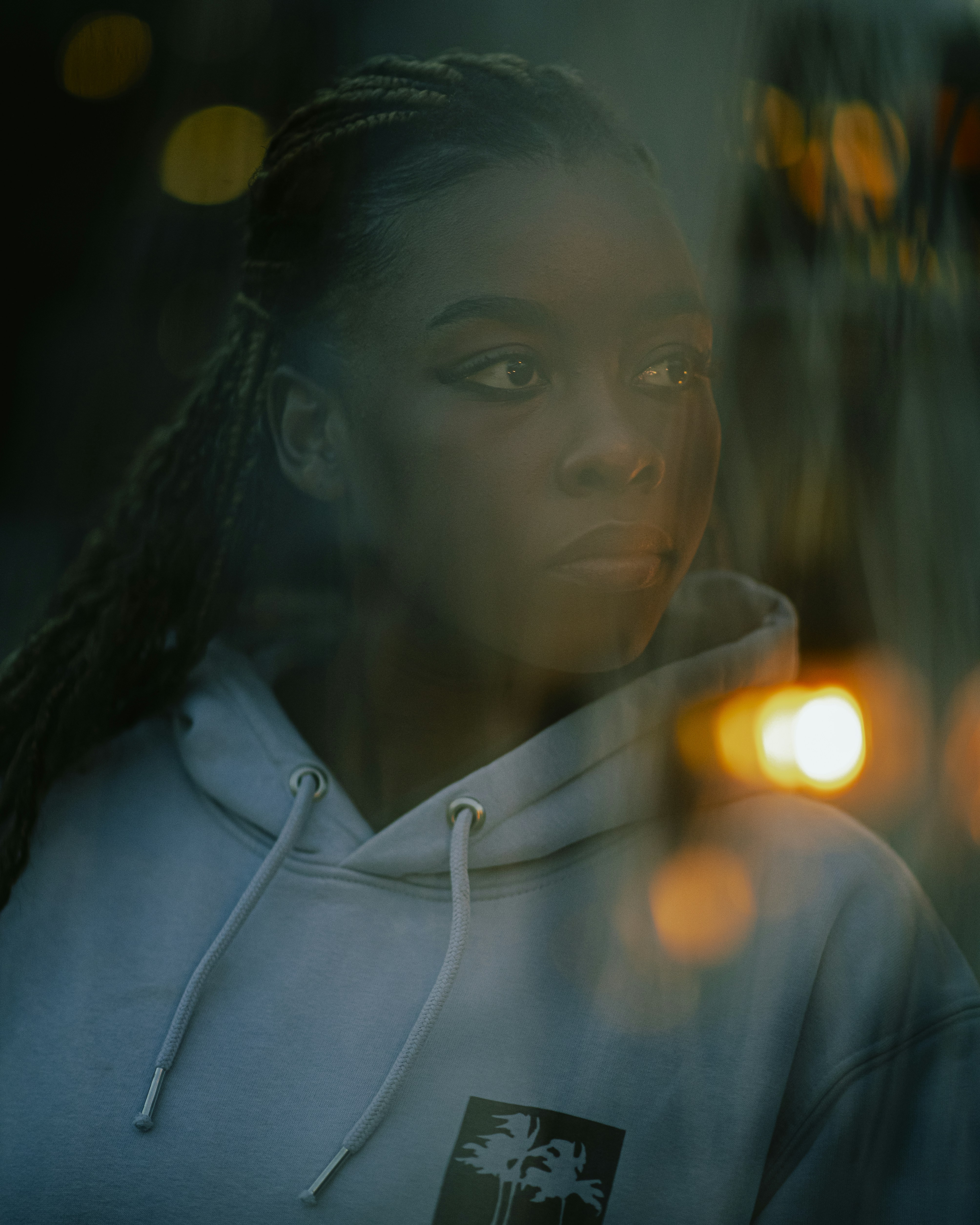 A woman looks thoughtful amidst bokeh lights.