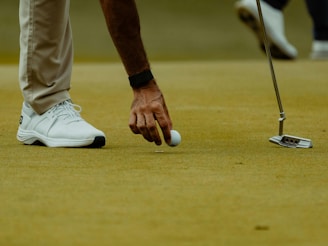 A golfer is picking up the ball on the green.