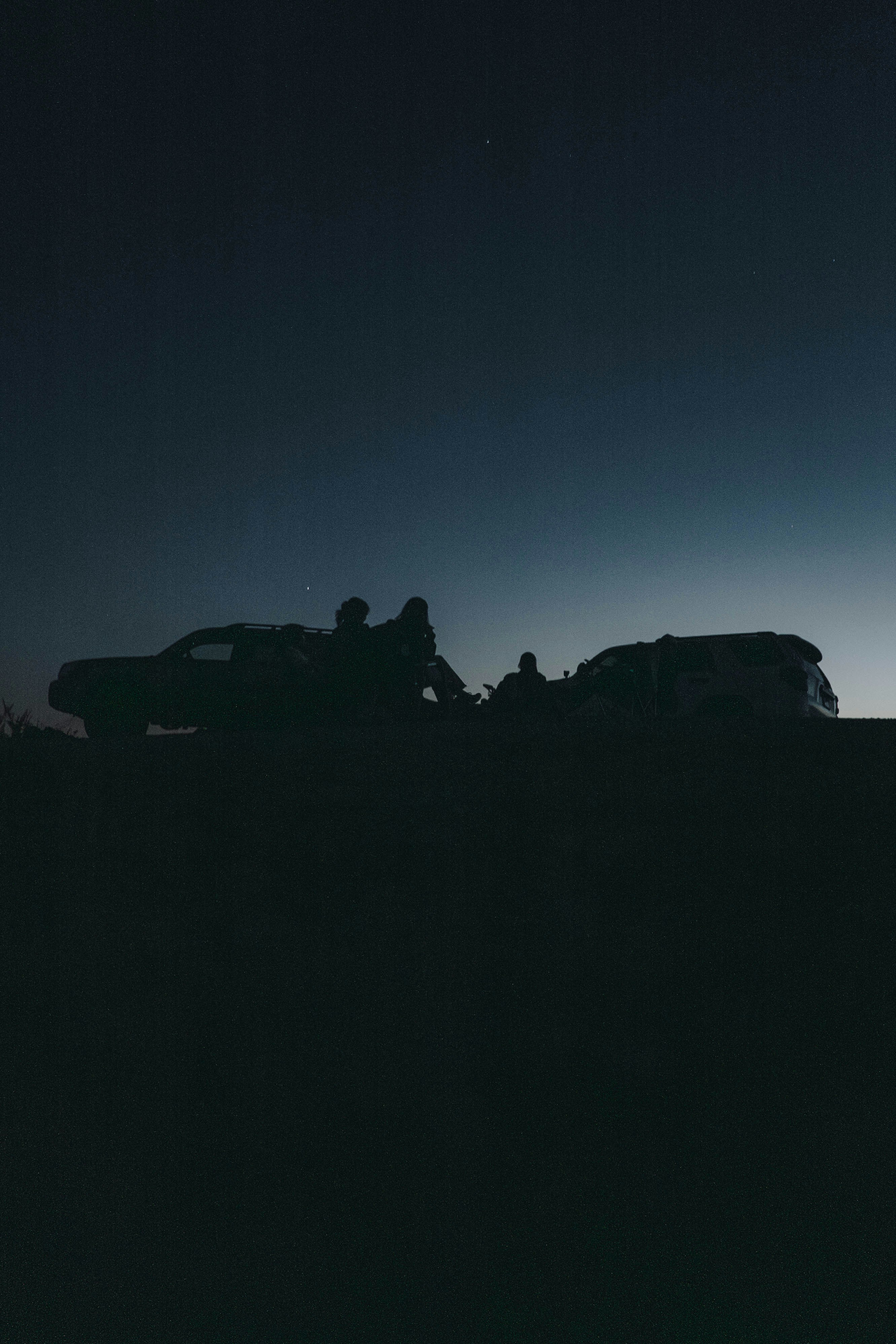People and cars silhouetted under a starry night.