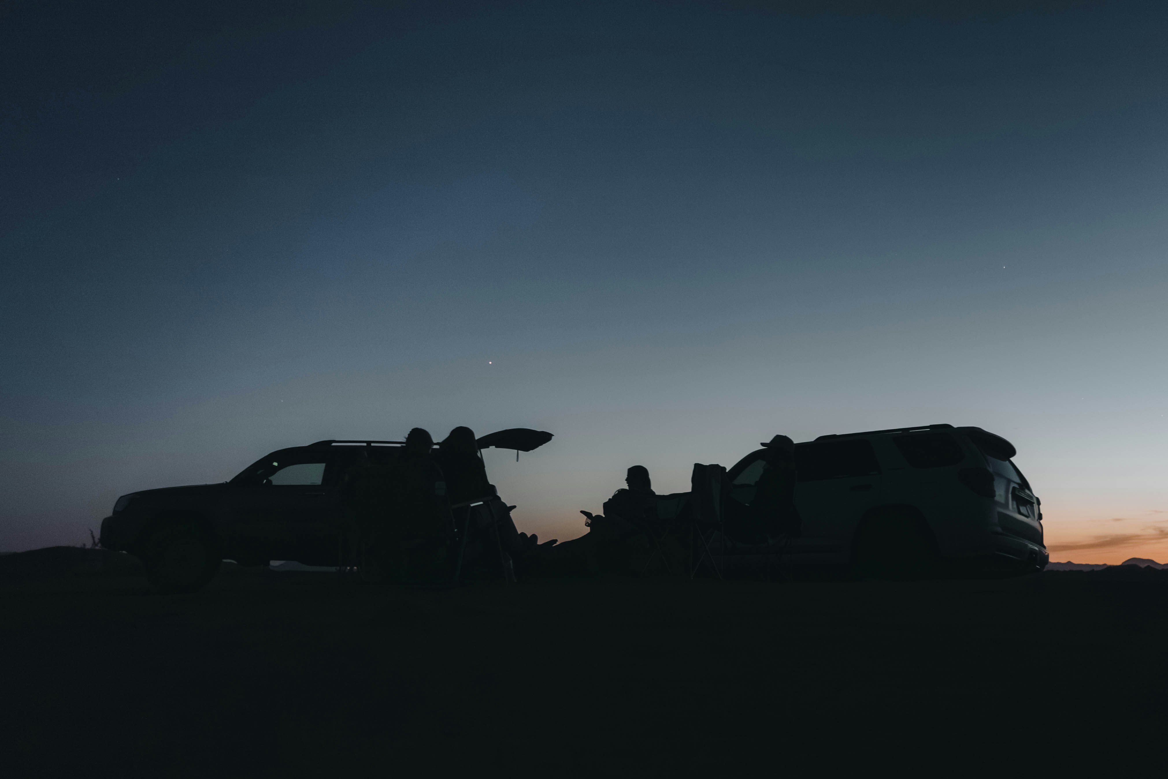 People sit around cars during dusk.