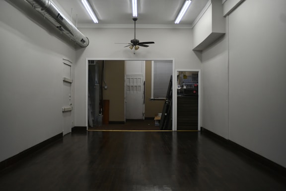 Empty room with multiple doorways and a ceiling fan.