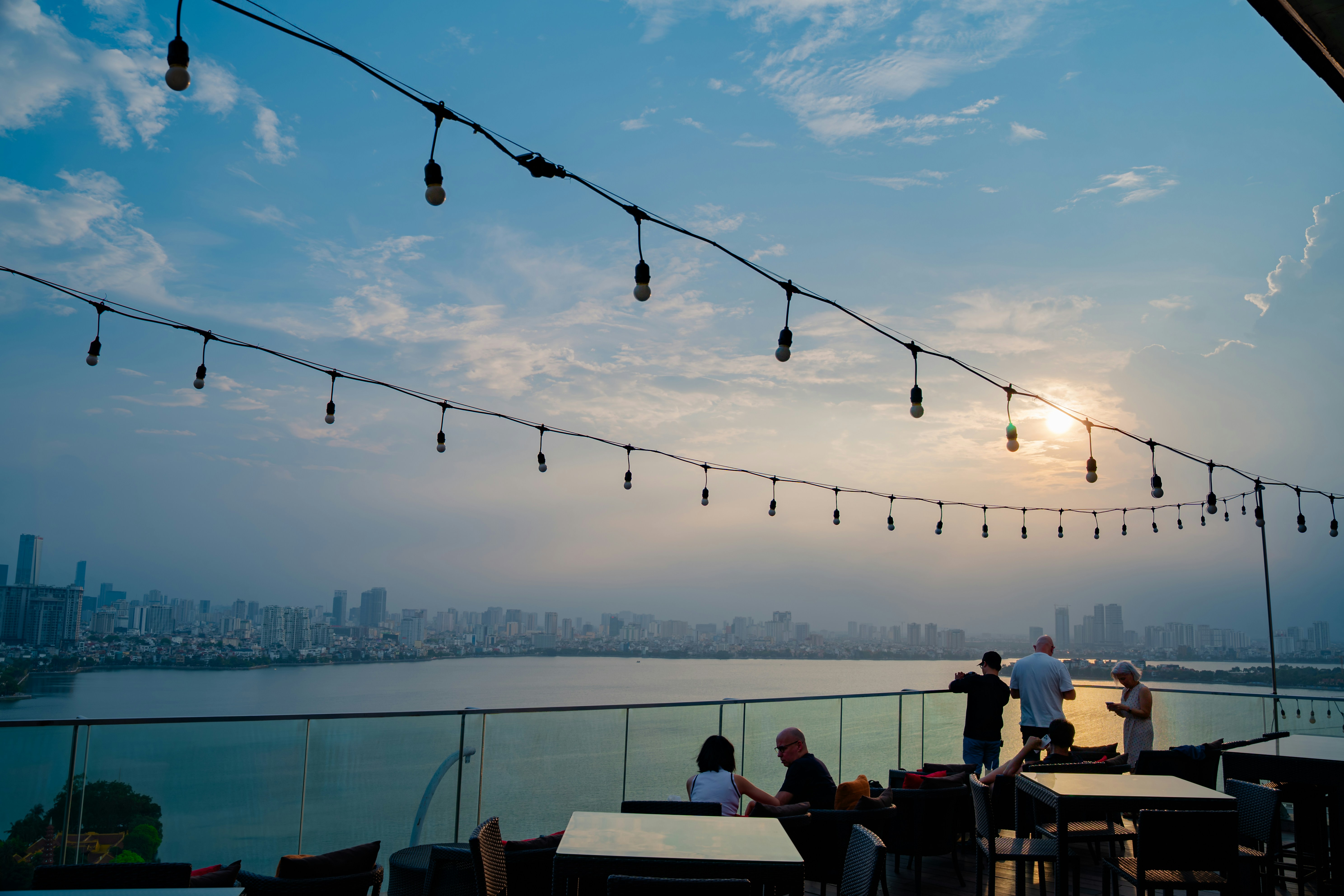 A stylish rooftop lounge at dusk with residents socializing and a Chicago skyline view - resort style apartments near me