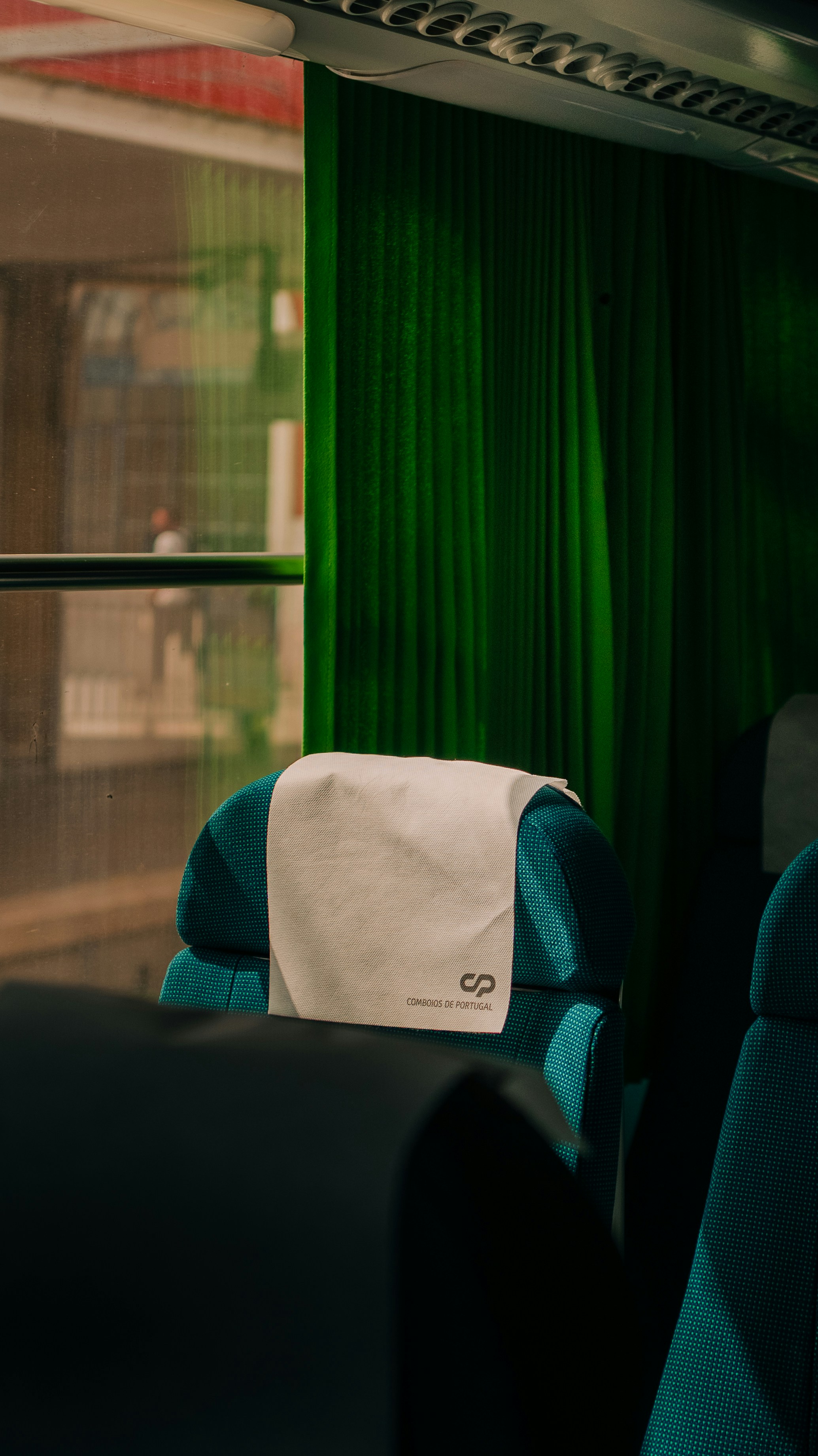 Train seat with green curtains.