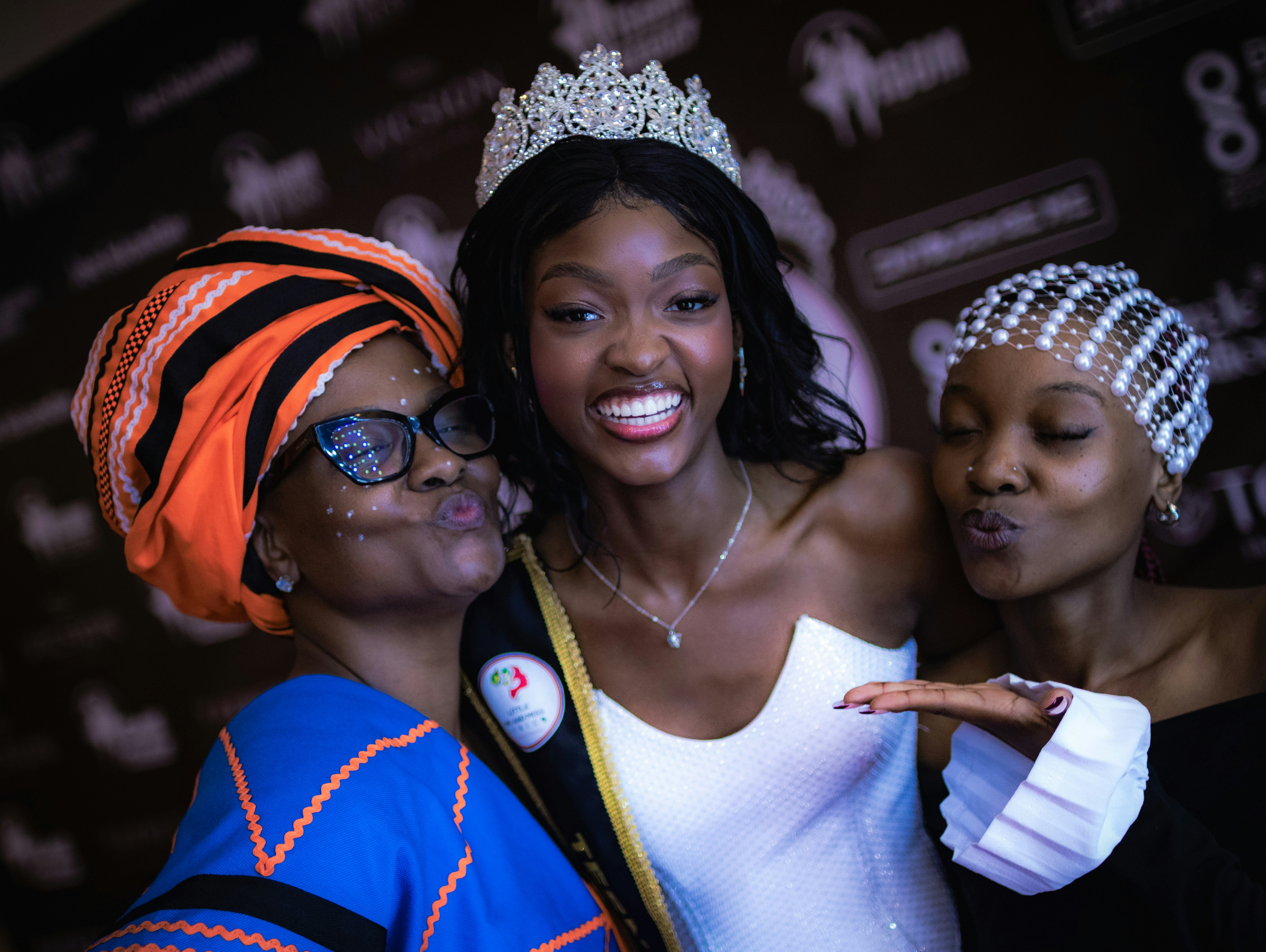 A beauty queen smiles with two women.