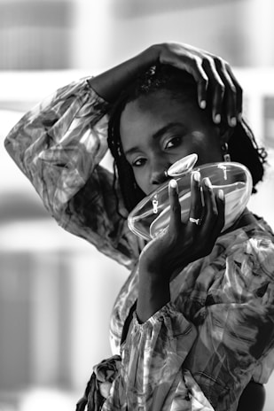 A woman poses with glass object in black and white.