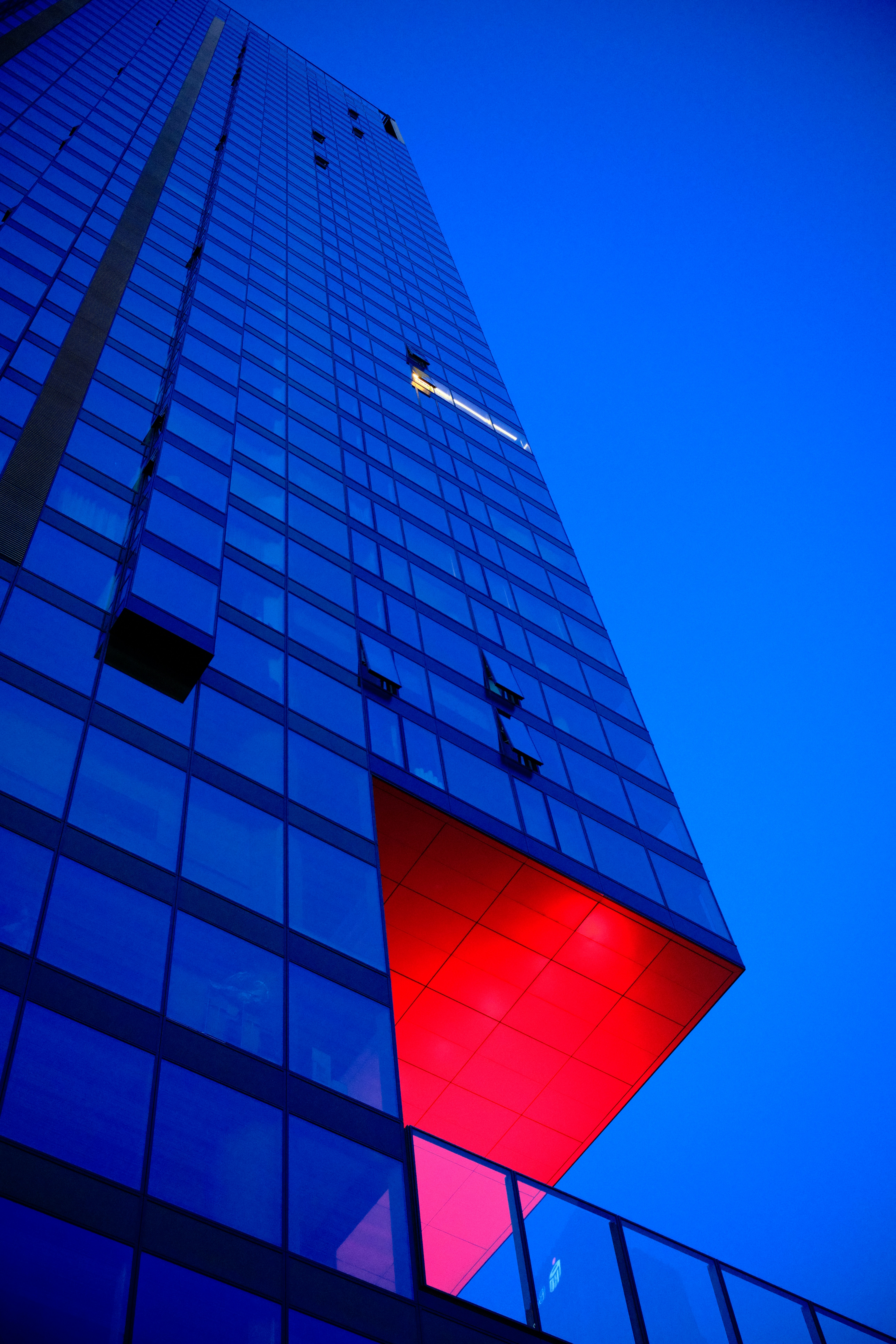 Blue skyscraper with a red, geometric shape.