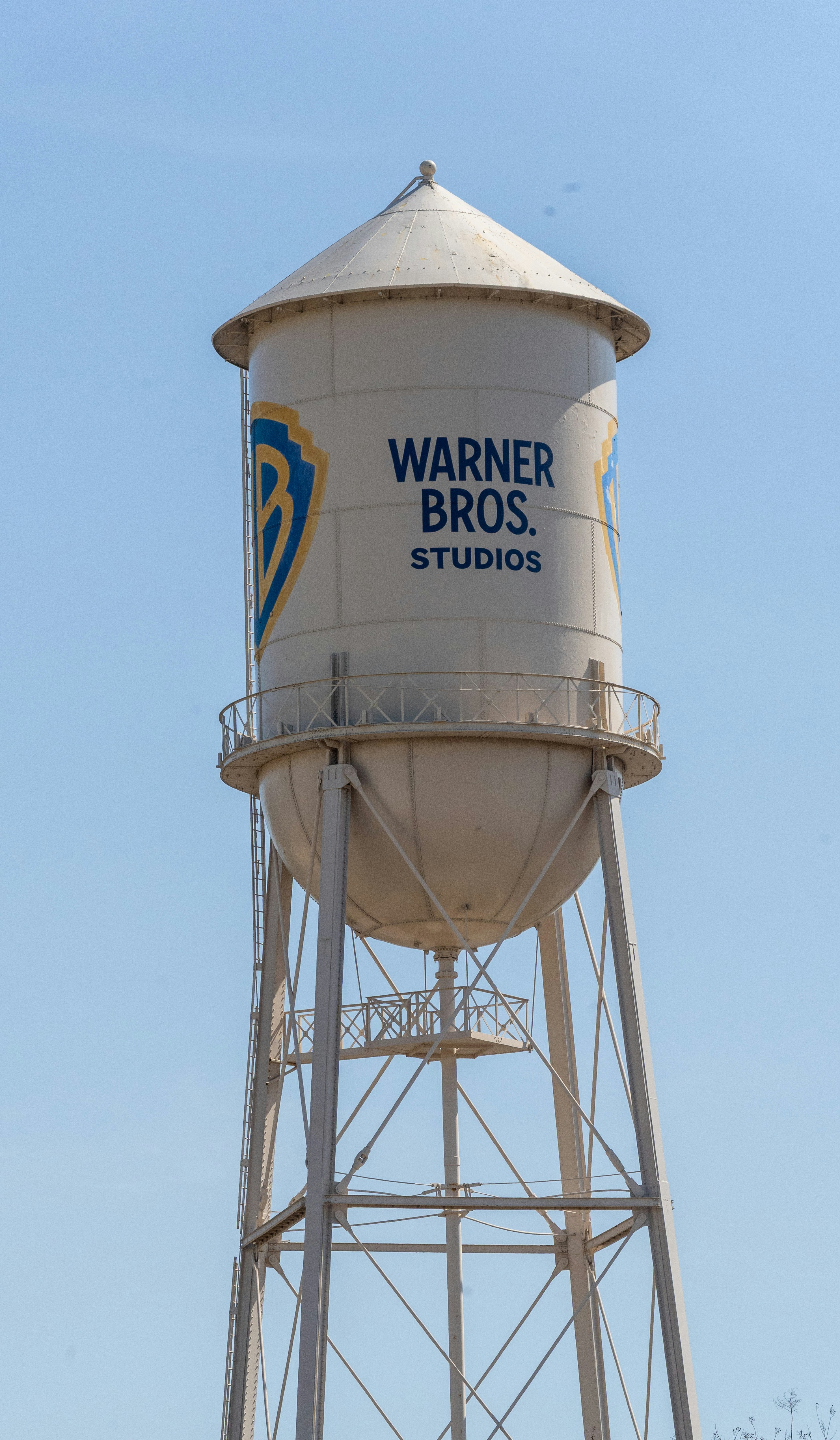 The iconic Warner Bros. Studios water tower rises against a clear blue California sky, a legendary symbol of Hollywood’s golden age and ongoing legacy in film and television production. Its bold logo and vintage structure evoke the timeless charm of the entertainment industry.