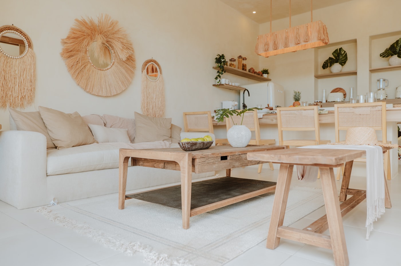 Warm minimalist apartment styled with linen sofa, raffia wall mirrors, light wood coffee table, and white walls for a soft natural look