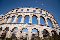 The roman amphitheater stands against a clear blue sky.