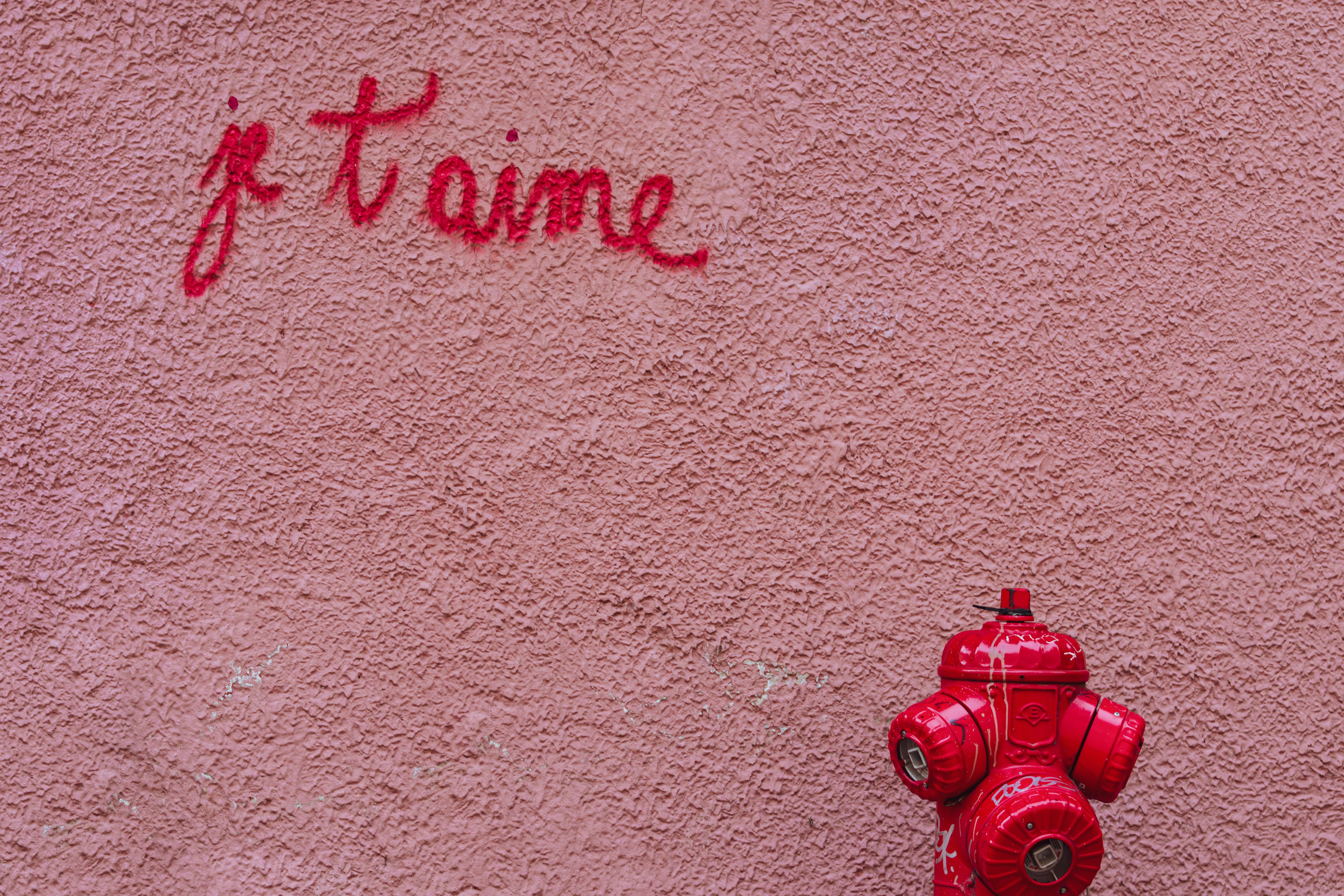 "je t'aime" is written on a pink wall.