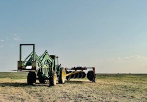 A tractor plows a field on a sunny day.