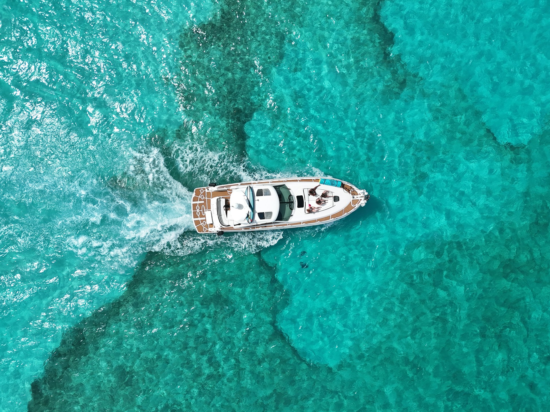 A boat speeds through crystal blue waters.