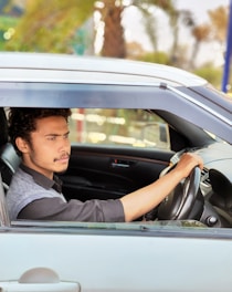 A young man drives a car on a sunny day.