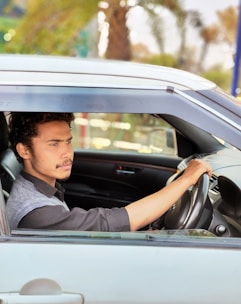 A young man drives a car on a sunny day.