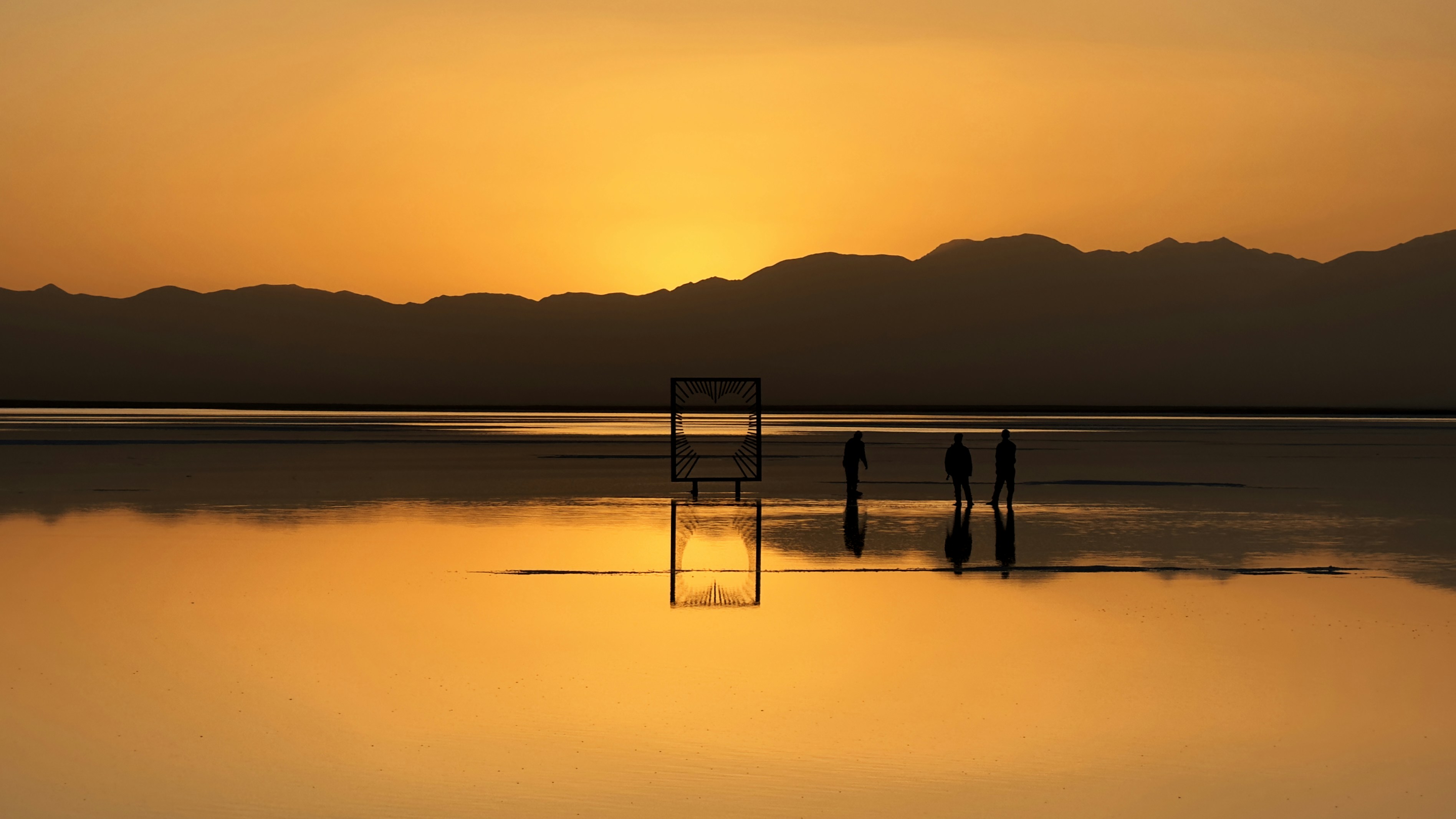 A stunning sunset over water with figures.