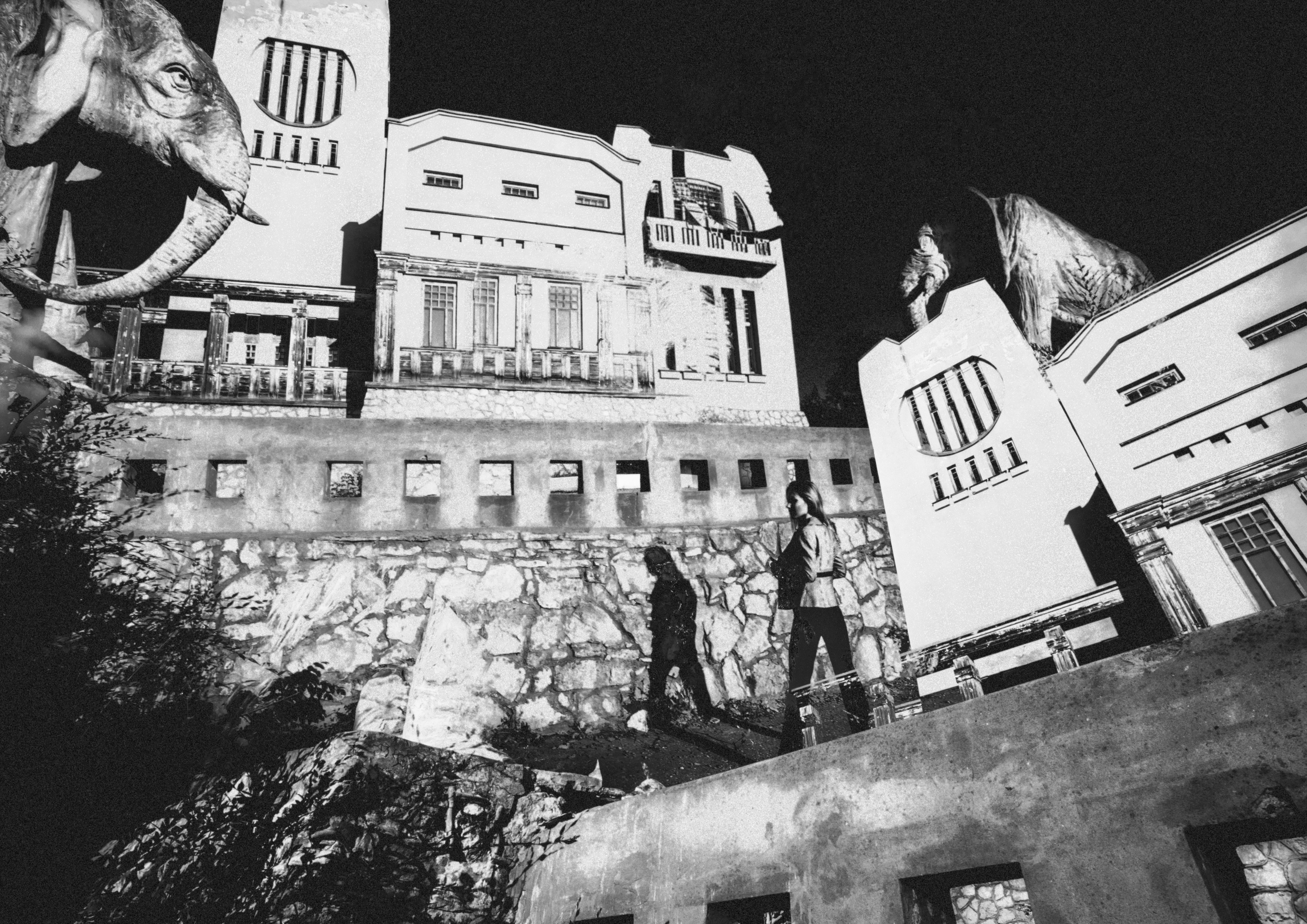 Deux personnes se tiennent sur un toit, surplombant un bâtiment.