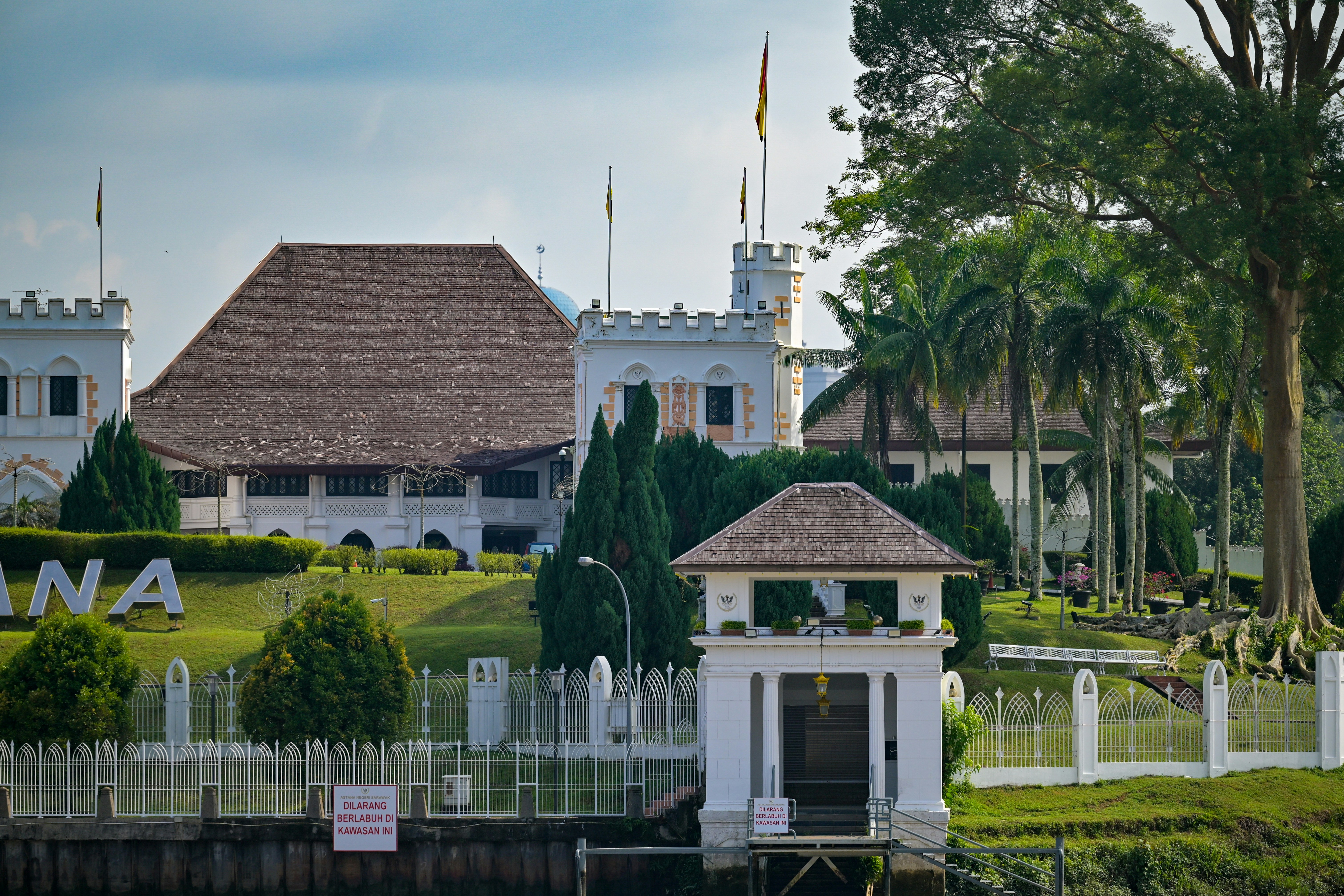 A white palace stands beside lush greenery.