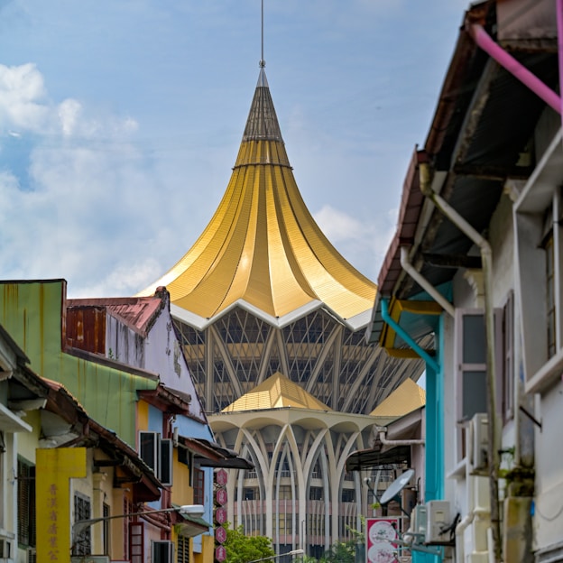 A striking golden building towers between colorful buildings.