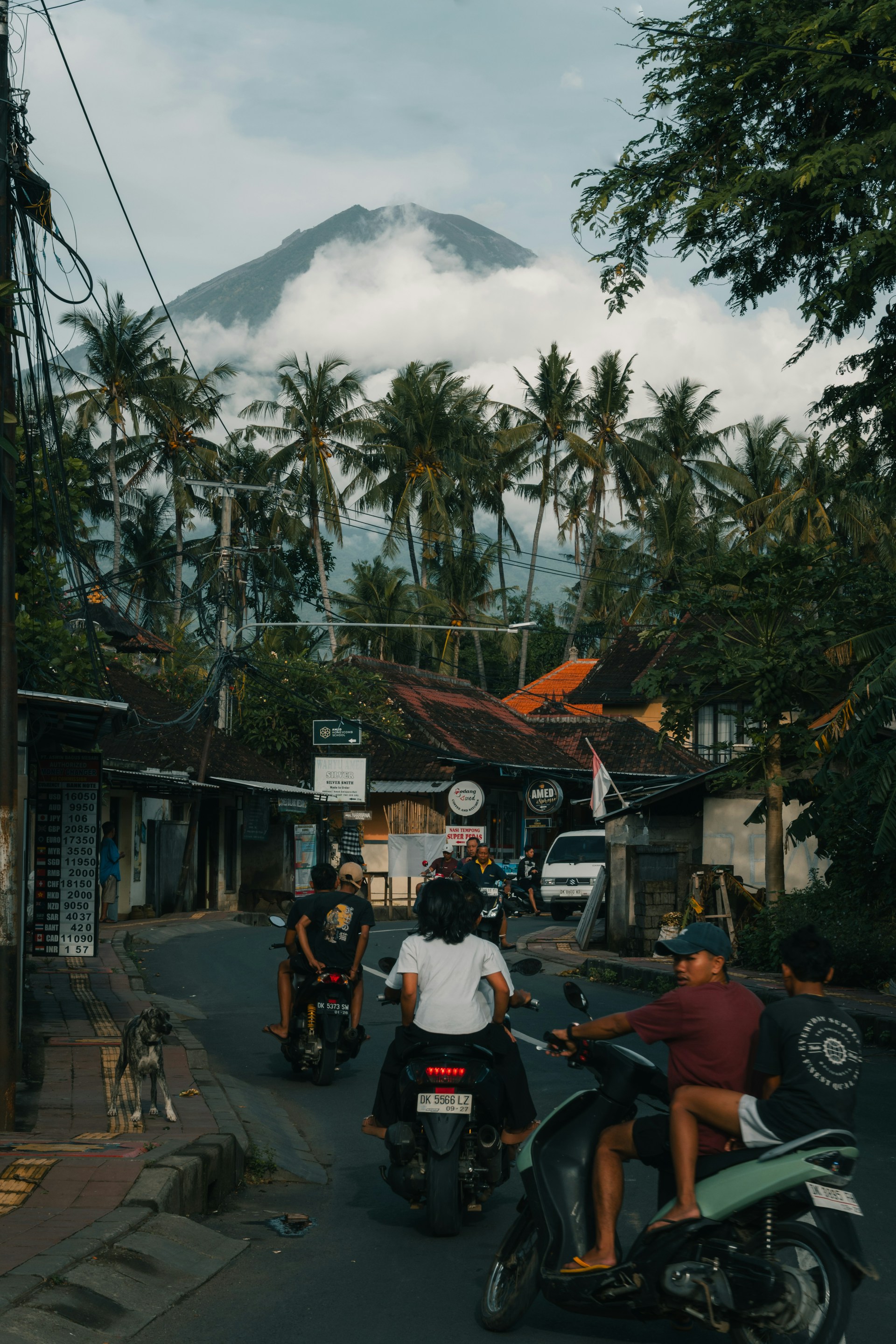 Motorcycles drive through a street with a mountain view.