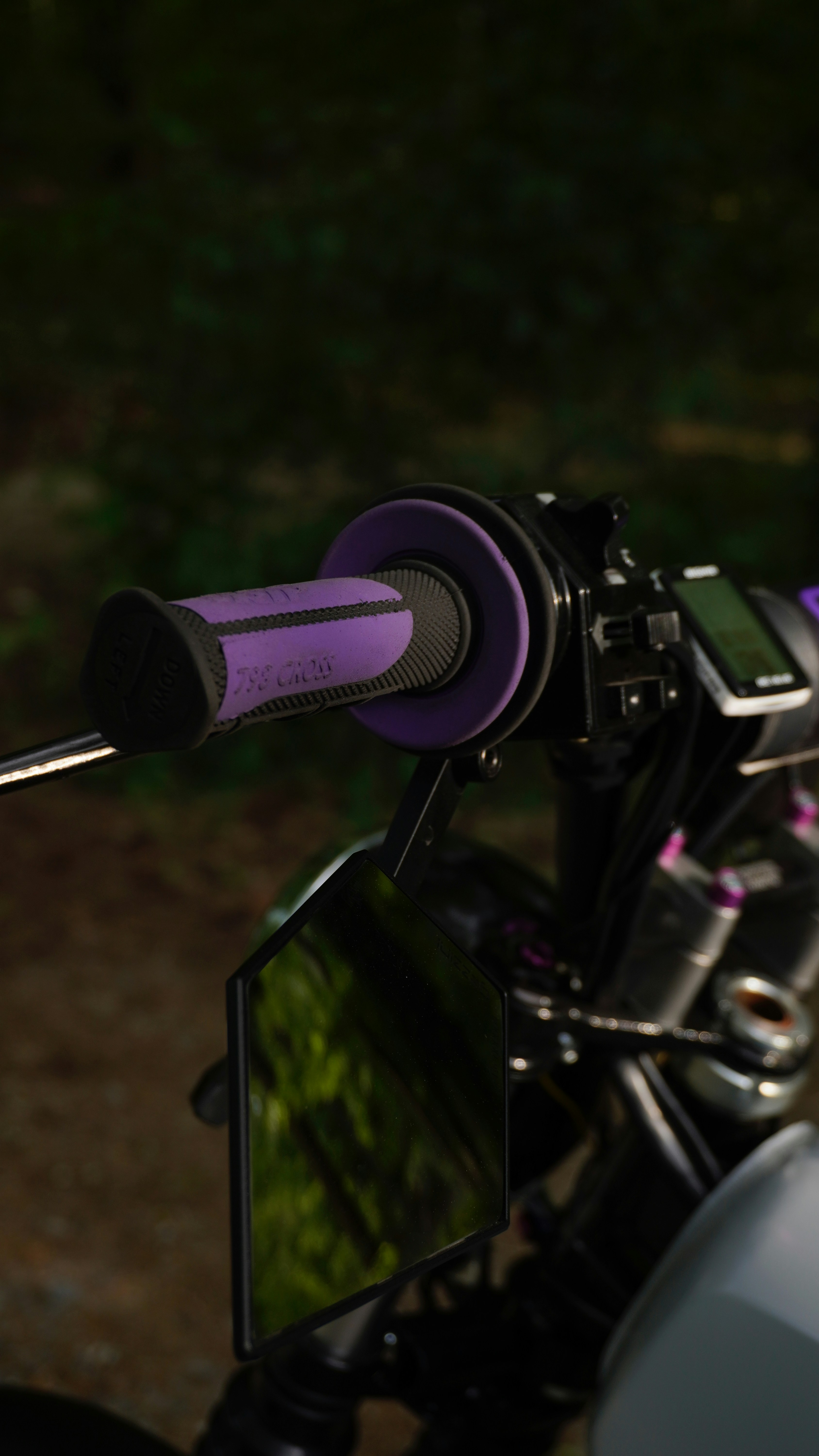 Motorcycle handlebars with purple grips are shown.