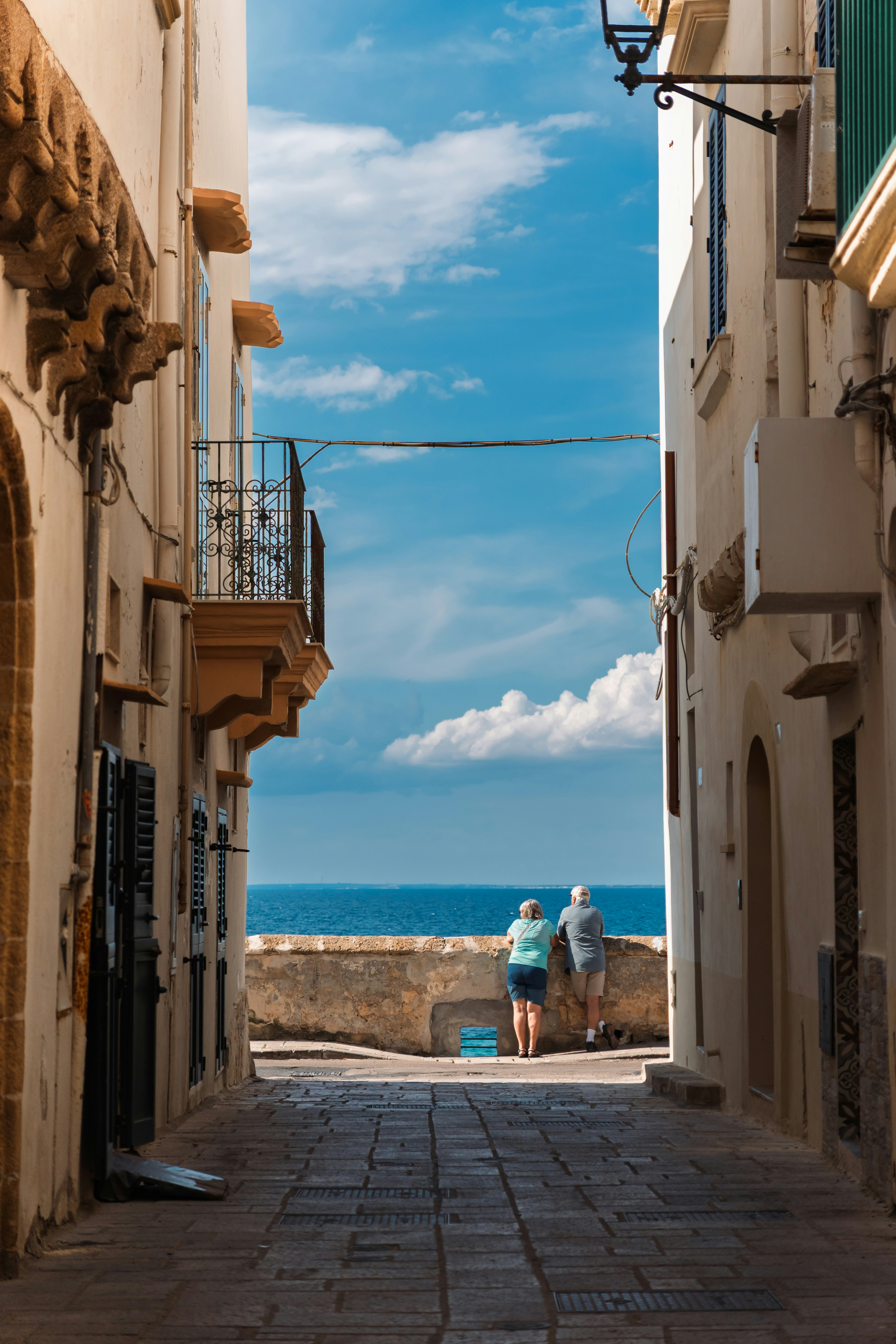 People gaze at the ocean from a narrow alley.