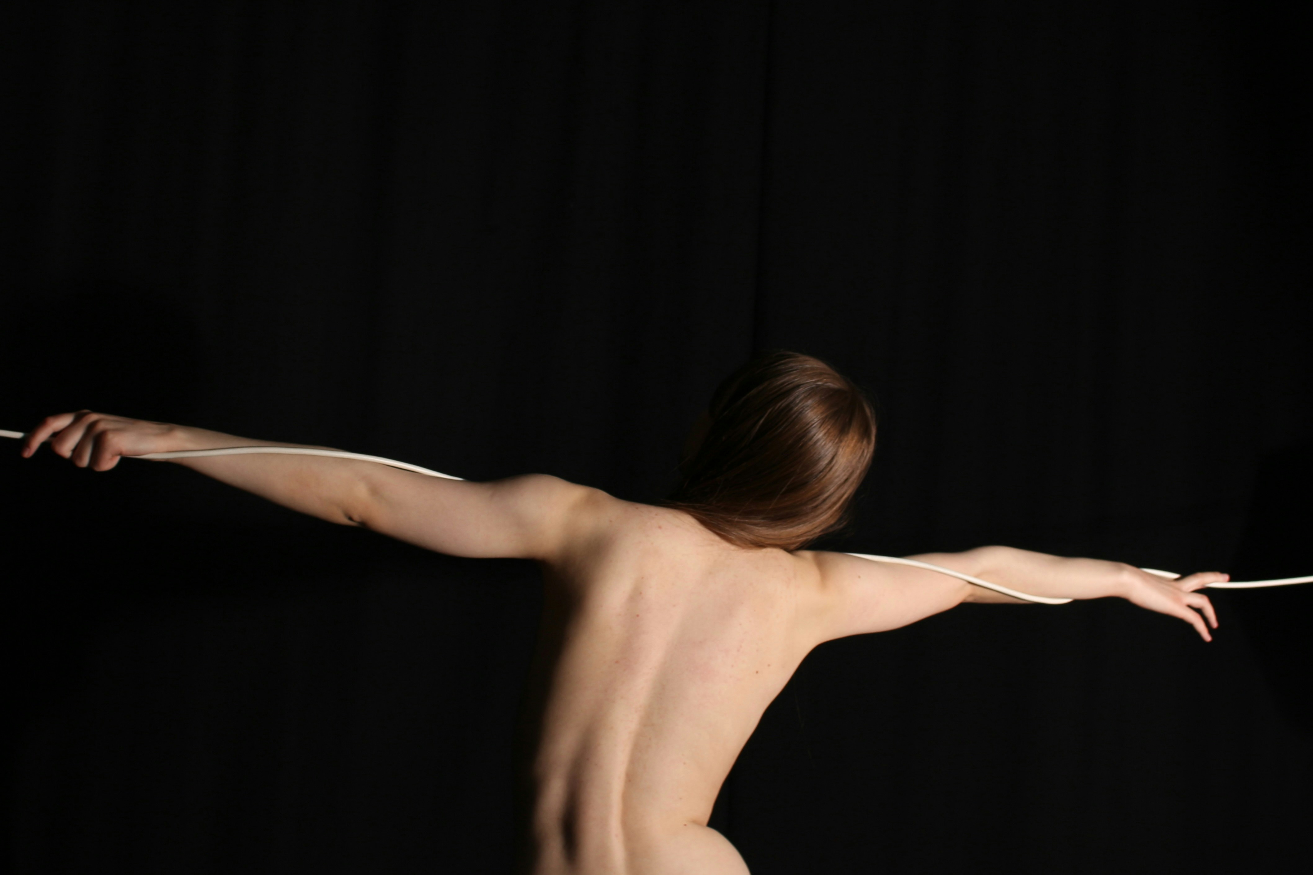 A person holds a rope, arms outstretched.