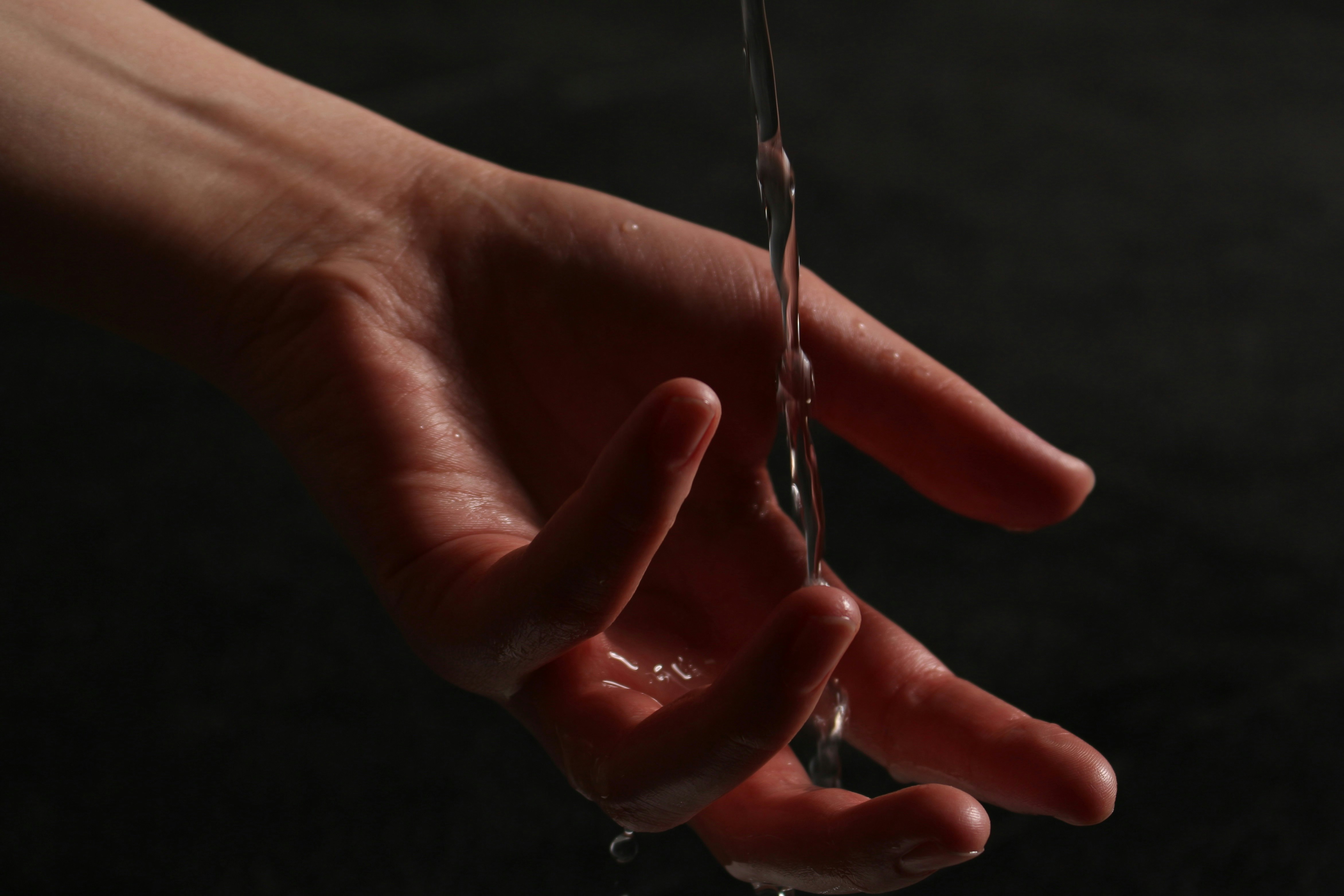 Water flows over a hand in a dark setting.