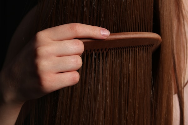 A hand combs long, brown hair.