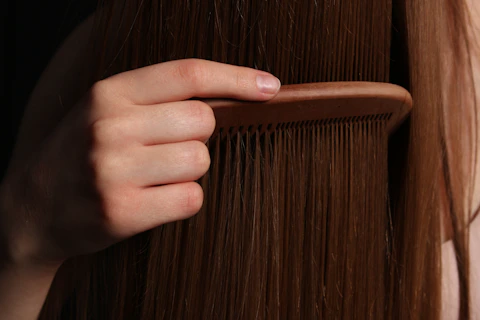 A hand combs long, brown hair.