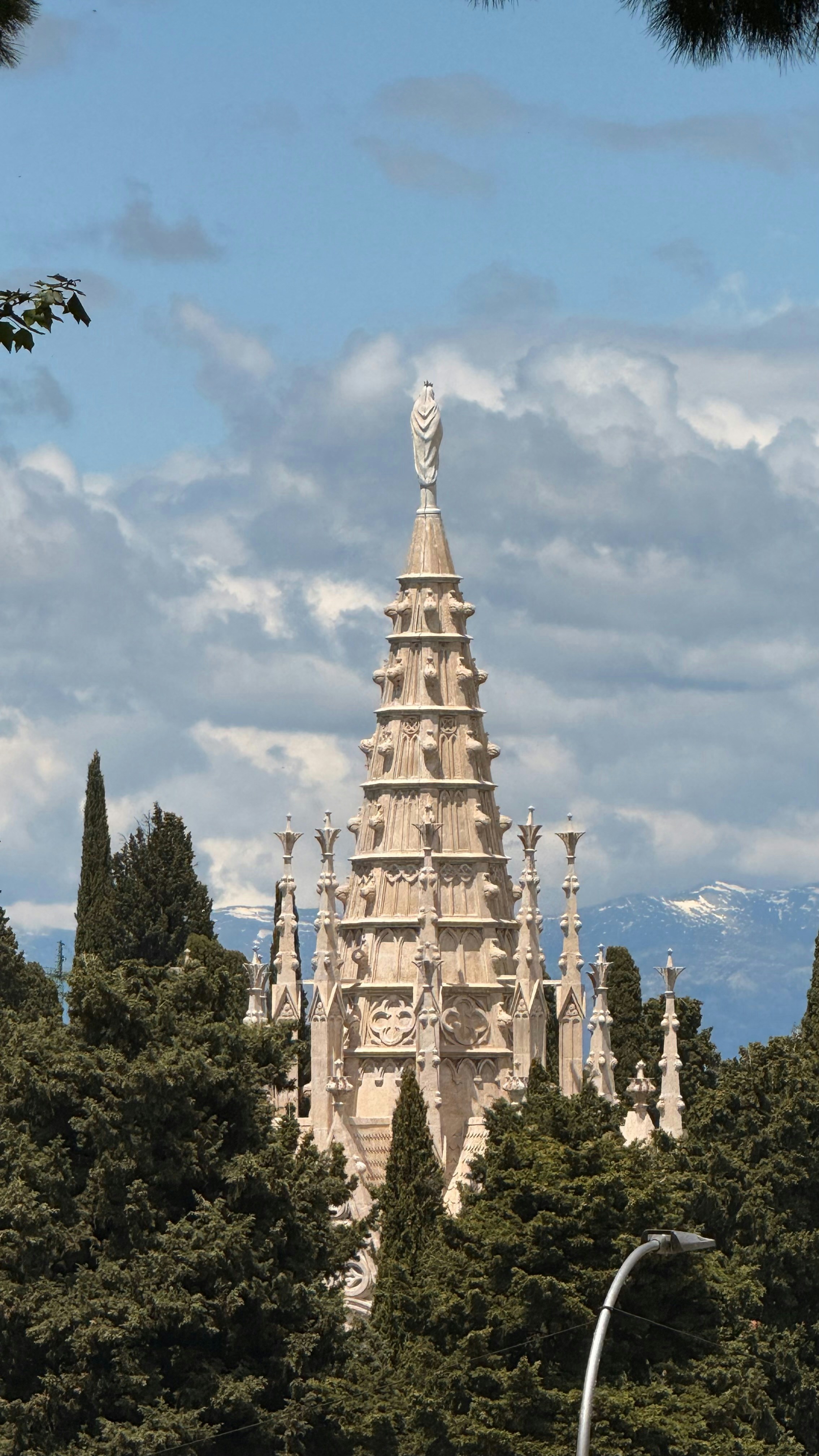 A tall, ornate structure is seen among trees.